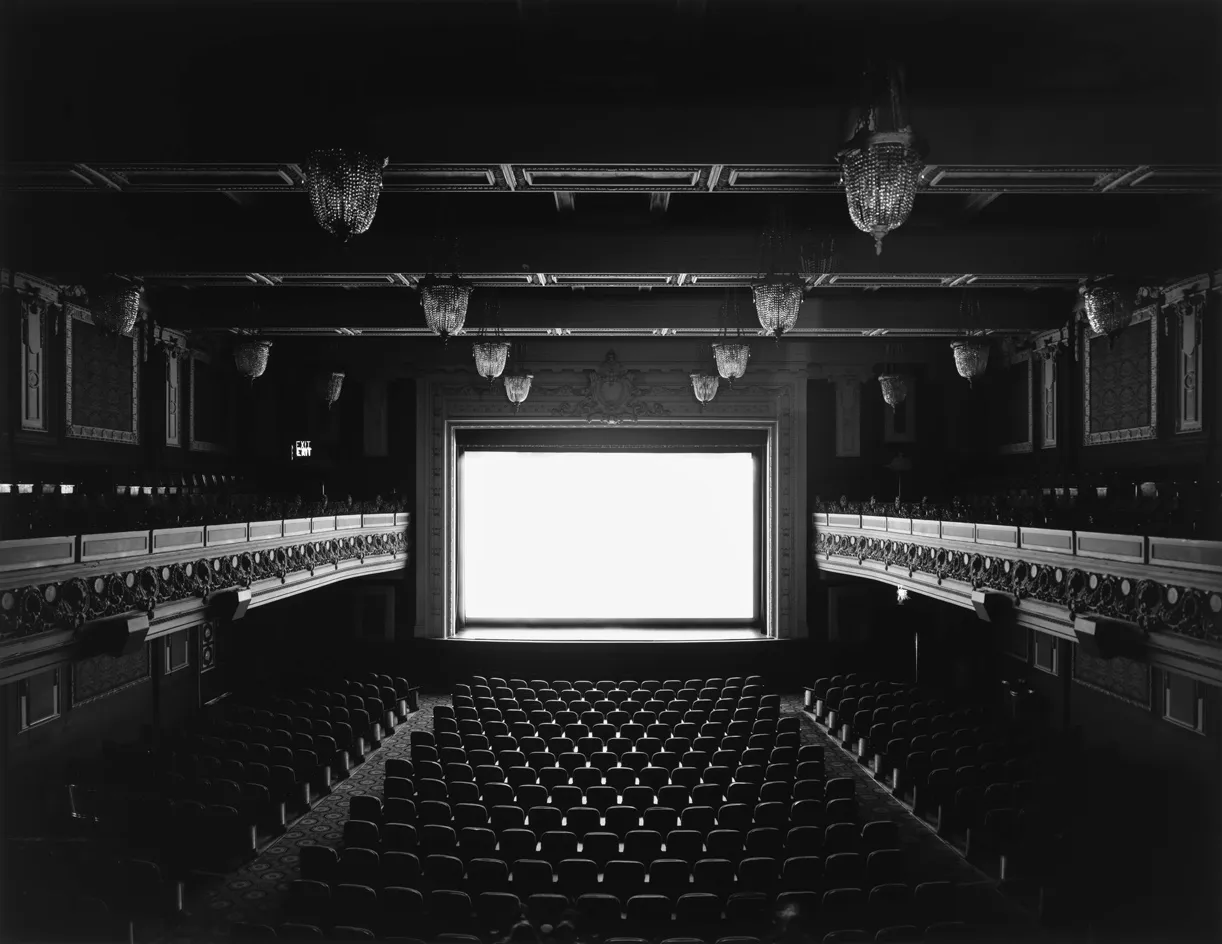 An empty art-deco cinema, screen glowing white